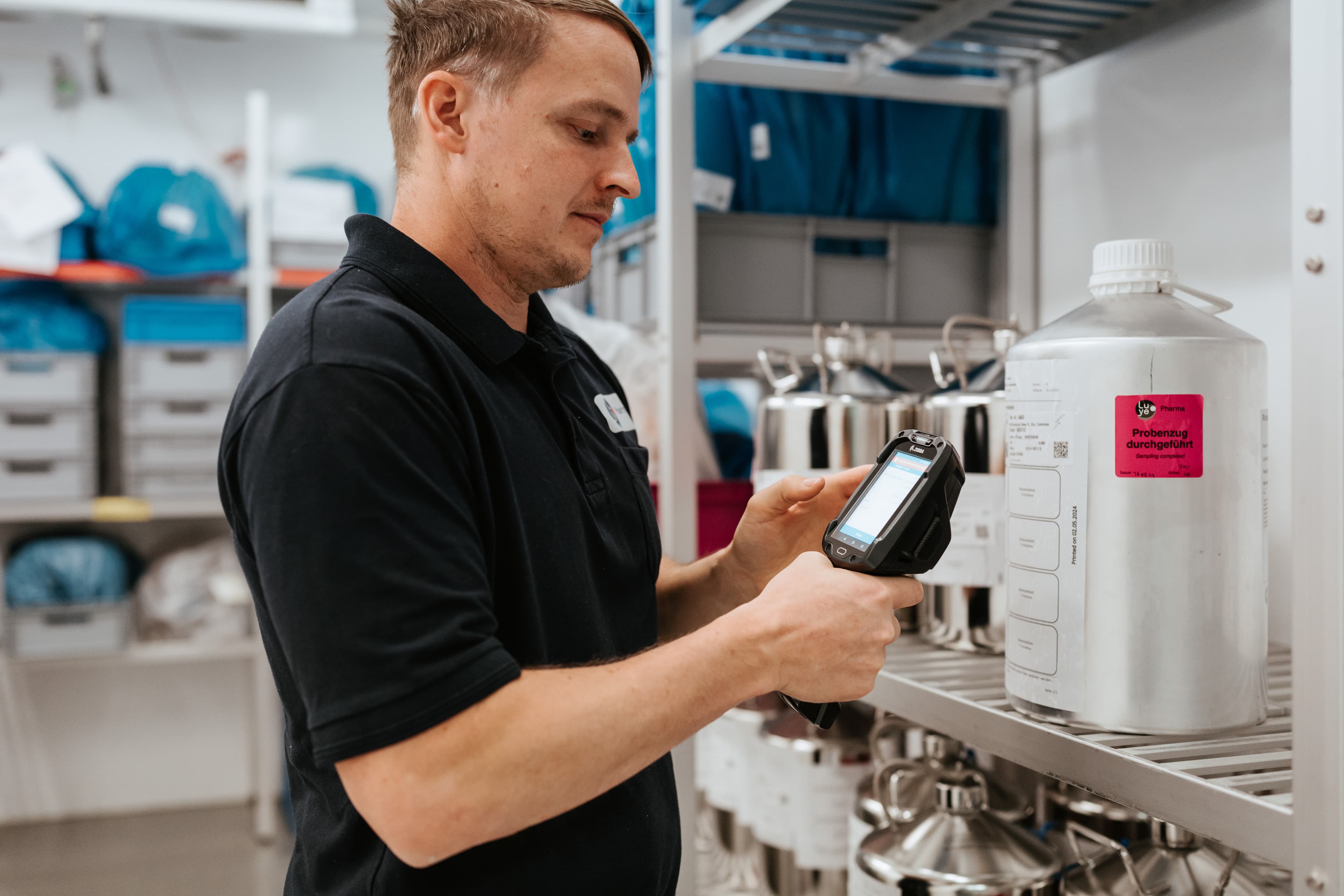 Ein%20Mann%20im%20schwarzen%20Poloshirt%20scannt%20mit%20einem%20Handscanner%20einen%20gro%DFen%20Metallbeh%E4lter%20mit%20der%20Aufschrift%20%27Probenzug%20durchgef%FChrt%27