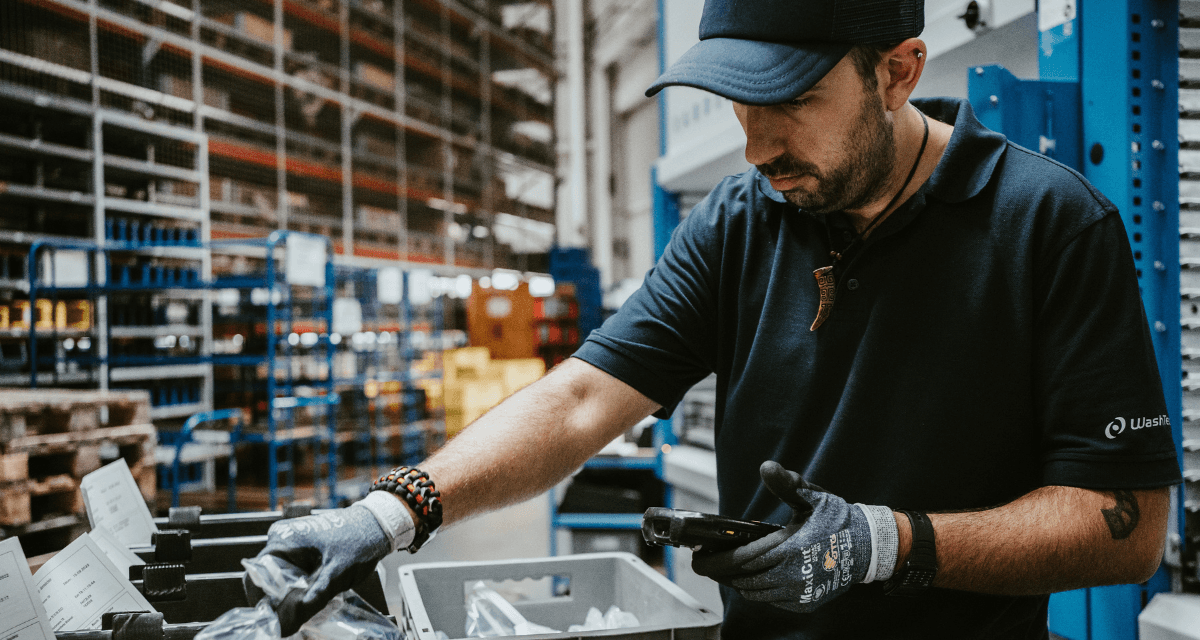 Ein%20Lagermitarbeiter%20bei%20WashTec%20kommissioniert%20Artikel%20aus%20RFID-Beh%E4ltern%20mit%20einem%20mobilen%20Scanner%20vor%20einem%20automatischen%20Kardex%20Shuttle%20Lagerlift.%20Dies%20veranschaulicht%20die%20Integration%20von%20SAP-Logistik%2C%20mobiler%20Datenerfassung%20und%20Smart%20Storage%20f%FCr%20schnellere%2C%20papierlose%20Prozesse.